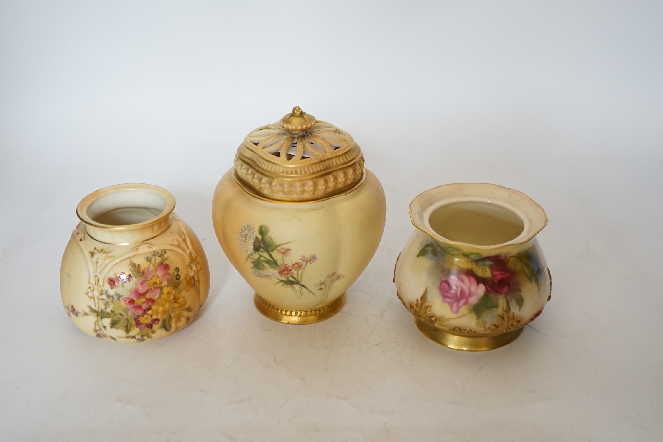 Three Royal Worcester blush ivory pots, one with an inner lid and pierced outer lid, tallest 14cm